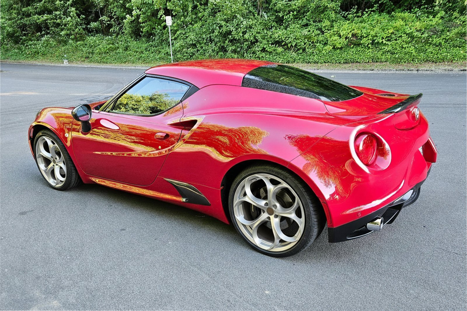 Красная Alfa Romeo 4C, вид сзади-сбоку, на тихой дороге