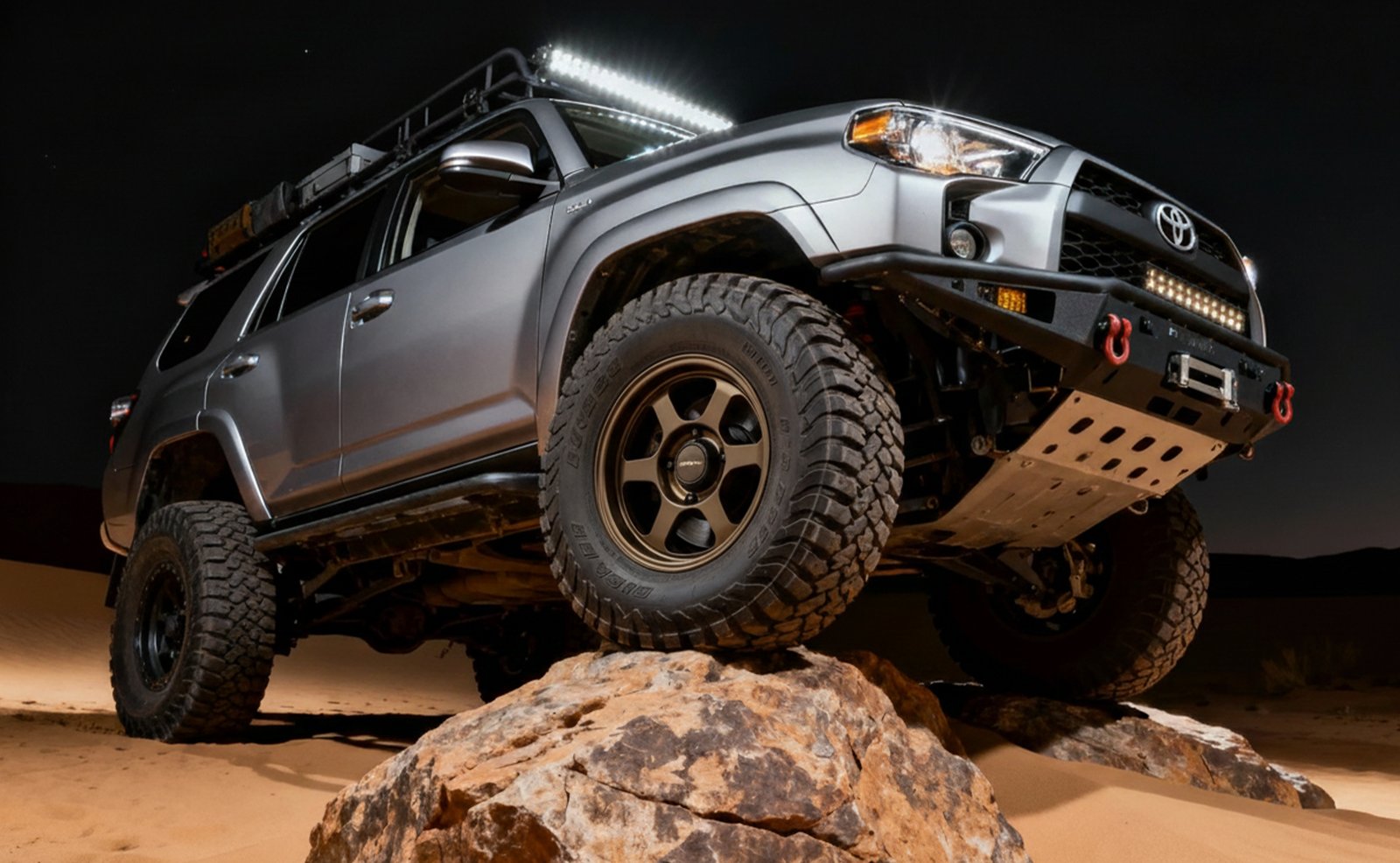 Поднятый Toyota 4Runner на скале ночью, нижний ракурс с люстрой на крыше