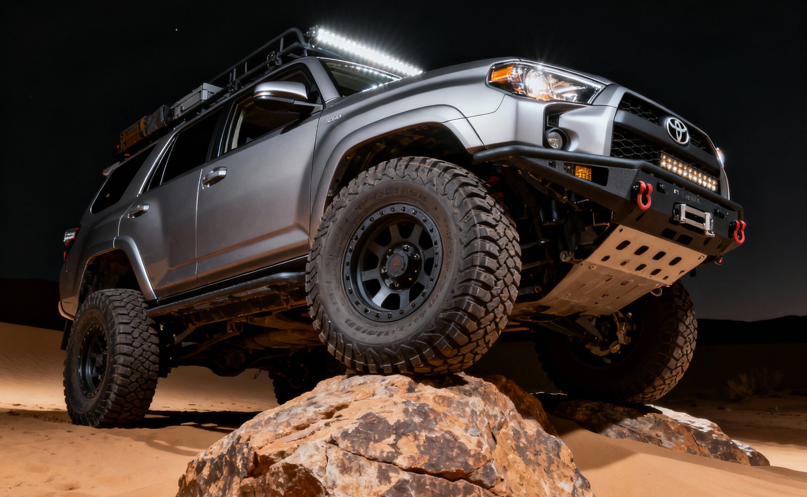 Поднятый Toyota 4Runner на скале ночью, нижний ракурс с люстрой на крыше